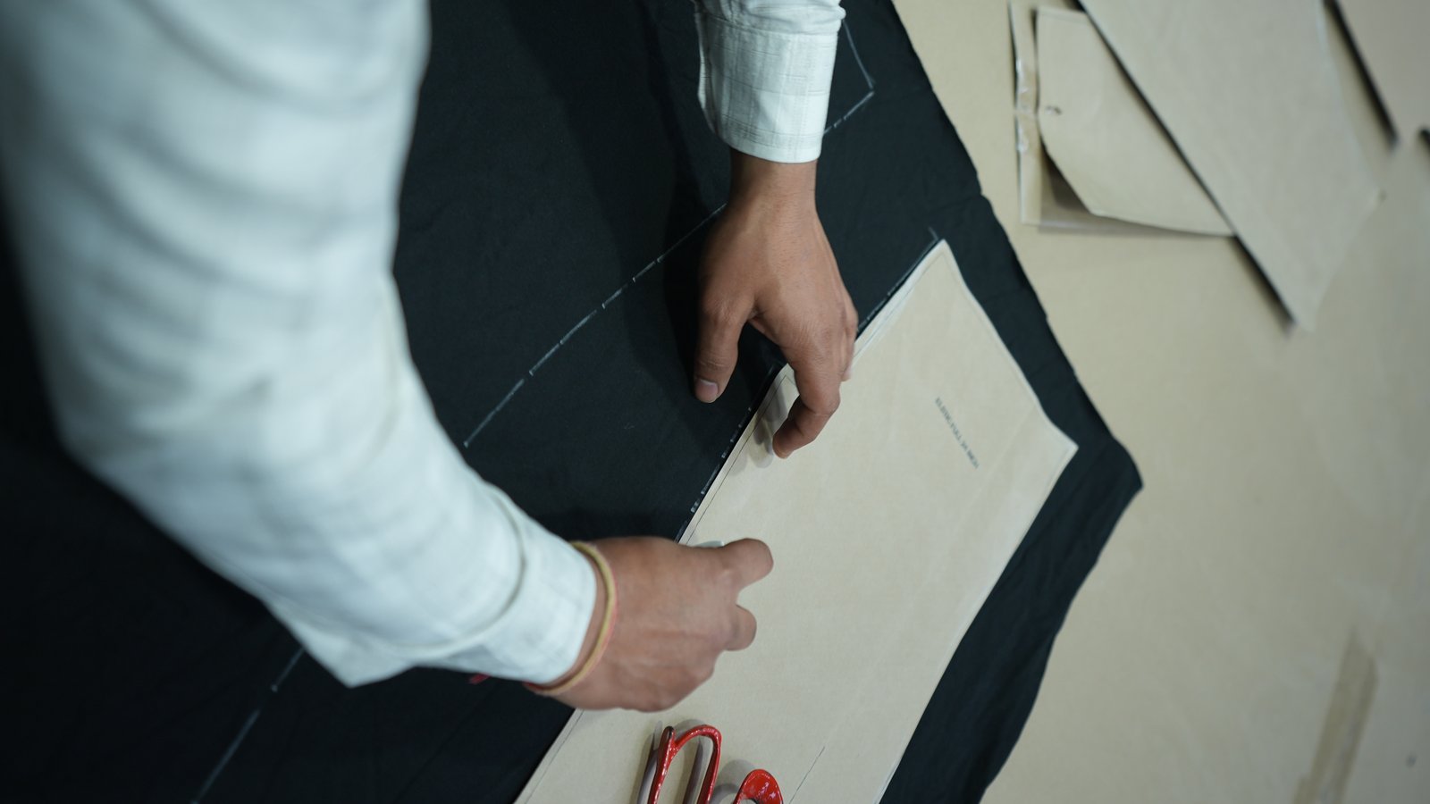 Paper pattern laid on dark fabric with red scissors
