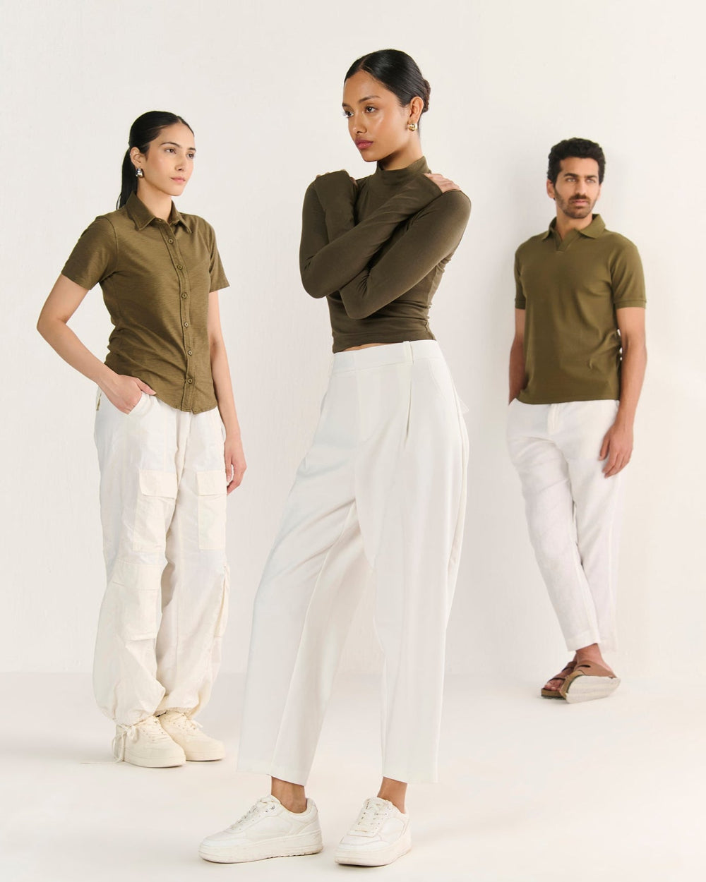 Three people wearing matching green polo shirts and white pants on a white background